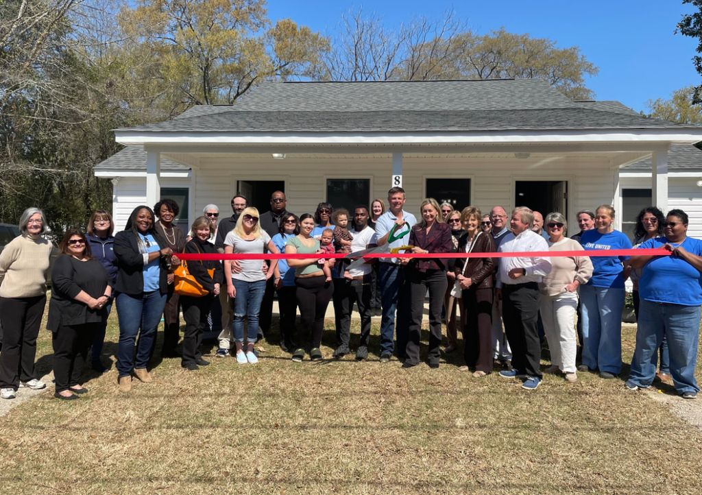 A ribbon-cutting ceremony took place at the United Way white building, and everyone involved gathered to take a picture in front of the building.