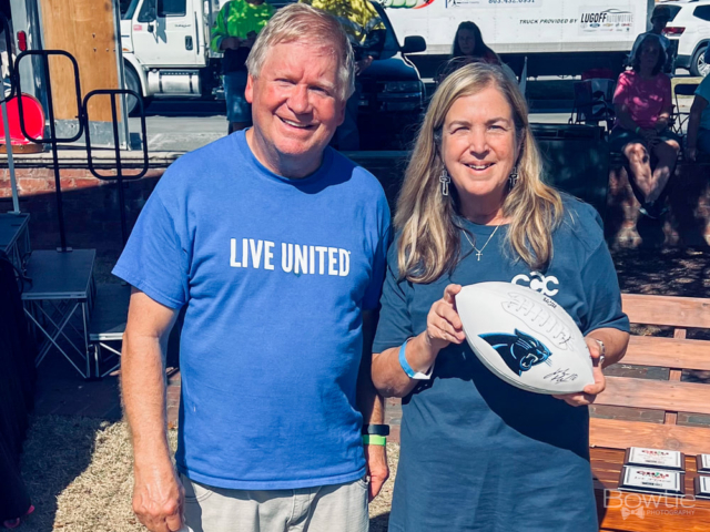 Imagine Donny, a young man, standing next to a girl. They are both holding a football with a panther signature on it.