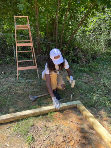 Imagine a scenario where a person is using wood and a hammer to create a border for a playset. The wood is being used to outline the play area, and the hammer is being used to secure the wood in place by driving stakes into the ground. This is similar to how a blind person might use their hands to feel and understand the shapes and materials being used to create the playset.