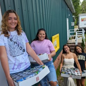 A group of young teenagers are bringing in cans of food to help people who need it.